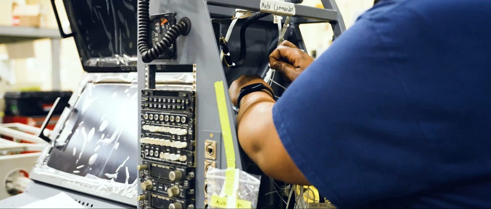 AME werkt aan elektrische componenten in missieconsole in hangar