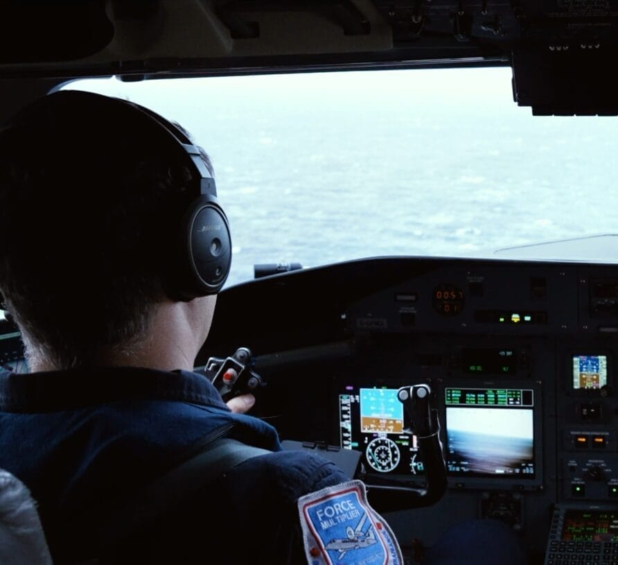 Piloto y copiloto en la cabina de un Dash 8-300 mirando el océano por el parabrisas.