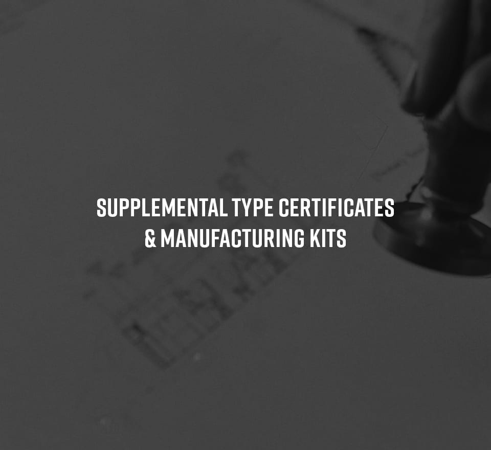 A close-up of a technical drawing with a hand holding a stamp, overlaid with the text SUPPLEMENTAL TYPE CERTIFICATES & MANUFACTURING KITS in bold white letters, highlighting aerospace engineering and certification.