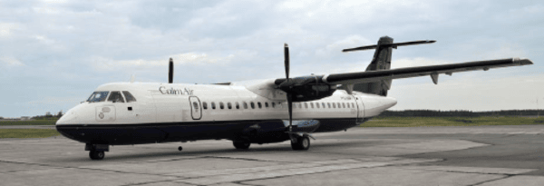 A white and dark blue propeller airplane equipped with an FMS sits on an airport tarmac under a cloudy sky, with grassy fields and trees visible in the background.
