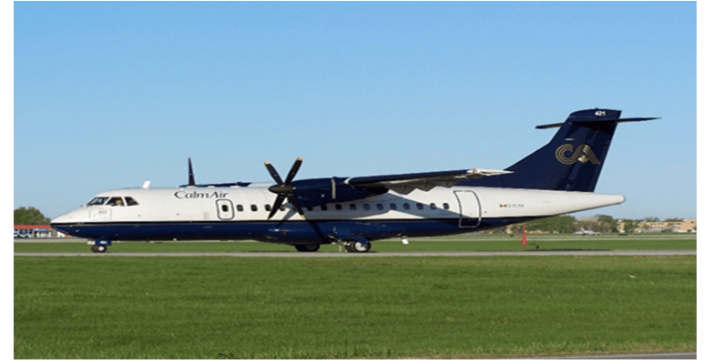 Un avión bimotor de hélice Calm Air, equipado con un transpondedor Garmin GTX-3000, está estacionado en una pista, con césped verde en primer plano y un cielo azul claro al fondo.