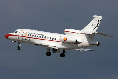 Un avión a reacción blanco con la inscripción «Fuerza Aérea Española» en el costado vuela contra un cielo nublado. Con marcas rojas y amarillas, cuenta con el tren de aterrizaje desplegado y está equipado con un sistema Honeywell TPA-100B actualizado a la versión TCAS 7.1.