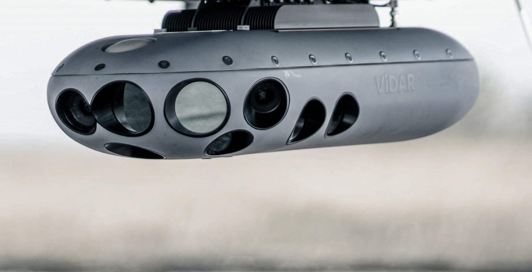 Primer plano de una cápsula gris para cámaras de vigilancia o reconocimiento, denominada ViDAR, que cuenta con múltiples lentes y sensores y está montada en una aeronave o un dron para las operaciones del Ministerio del Interior del Reino Unido.